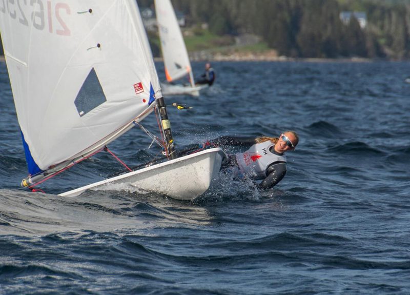 Annie Balasubramanian sailing an ILCA 6 upwind through spray.